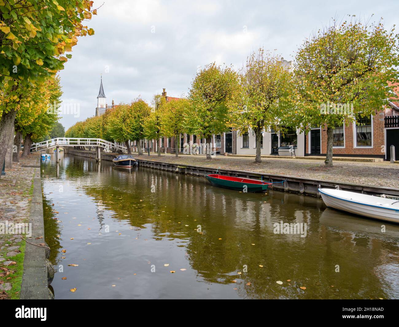 Puente peatonal sobre el canal y casas en Heerenwal muelle en la ciudad de Sloten, Sleat, Friesland, Países Bajos Foto de stock