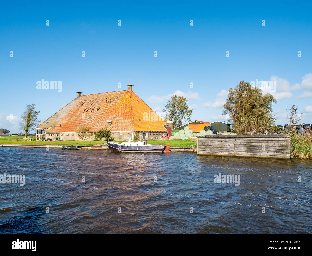 Casa de campo tradicional con techo grande a lo largo del canal Koarte Fliet en Gaastmeer, Frisia, Países Bajos Foto de stock