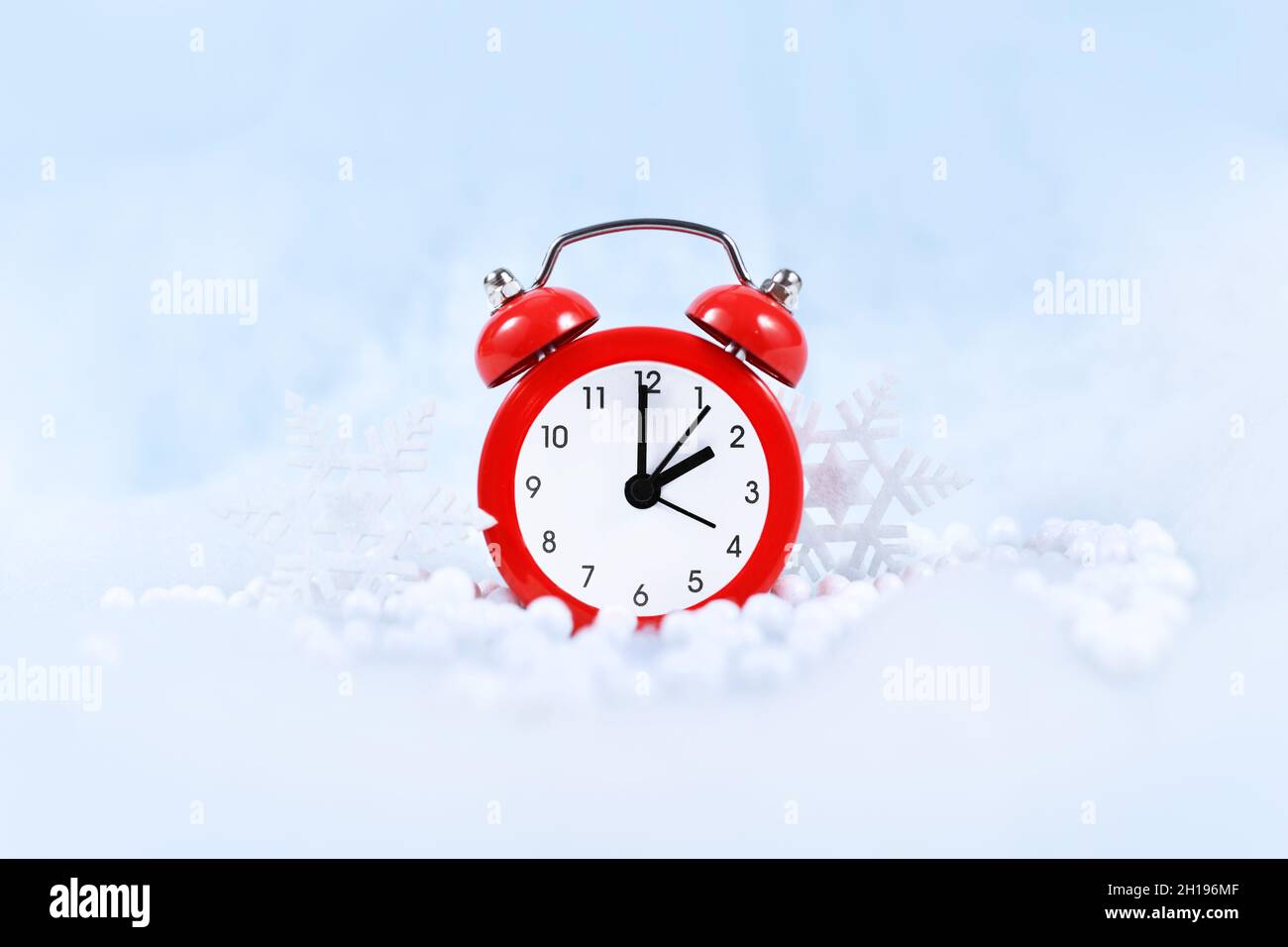 Cambio de hora de invierno para el horario de verano en Europa el 31st de octubre concepto con reloj de alarma rojo entre nieve Foto de stock