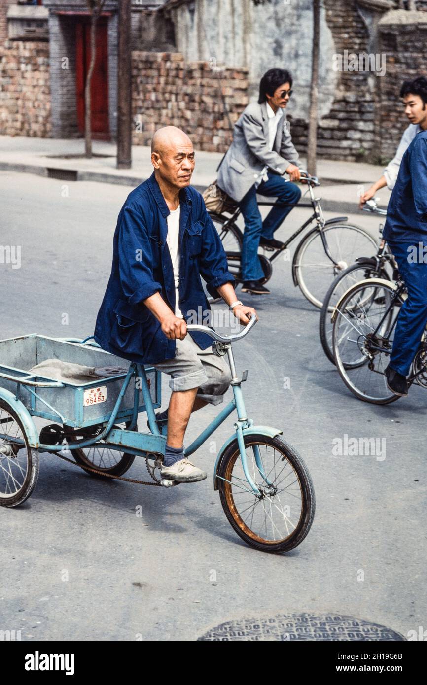 Un hombre chino montando su triciclo carga en la calle en Beiing, China Fotografía de stock - Alamy