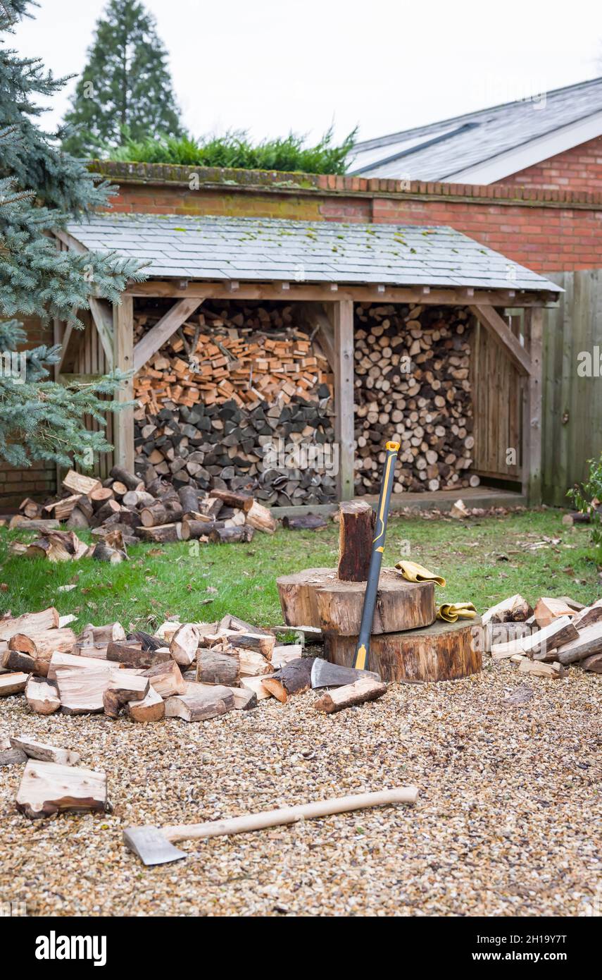 Pila de troncos con leña cortada en el exterior de una tienda de troncos en un jardín del Reino Unido. Describe el concepto de energía renovable, biomasa y biocombustible Foto de stock