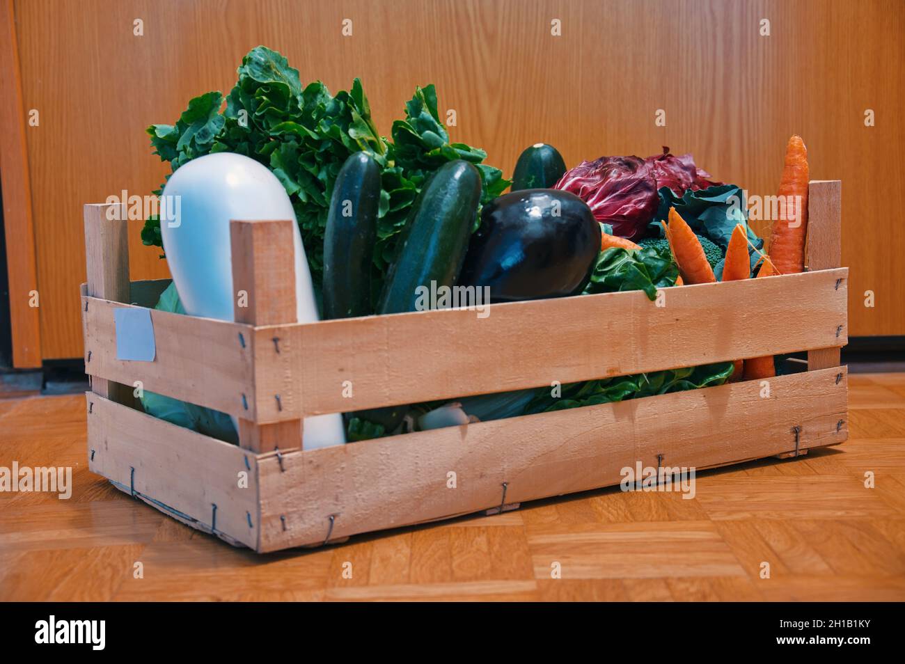 Verduras saludables en caja de madera entregada a la puerta principal Foto de stock