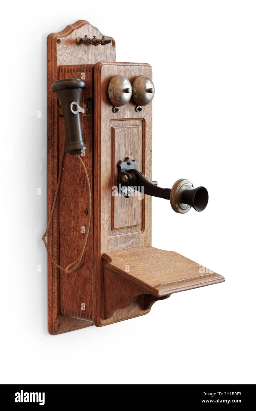 Objetos aislados: Teléfono de madera muy antiguo, montado en la pared, sobre fondo blanco Foto de stock