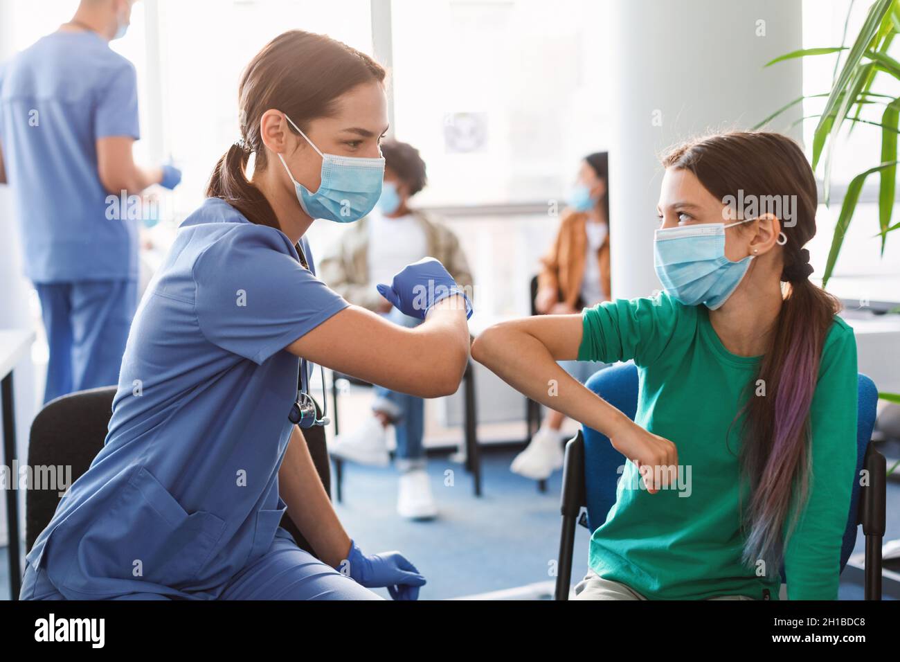 Adolescente en la máscara médica Codos de choque con el médico de la reunión Foto de stock