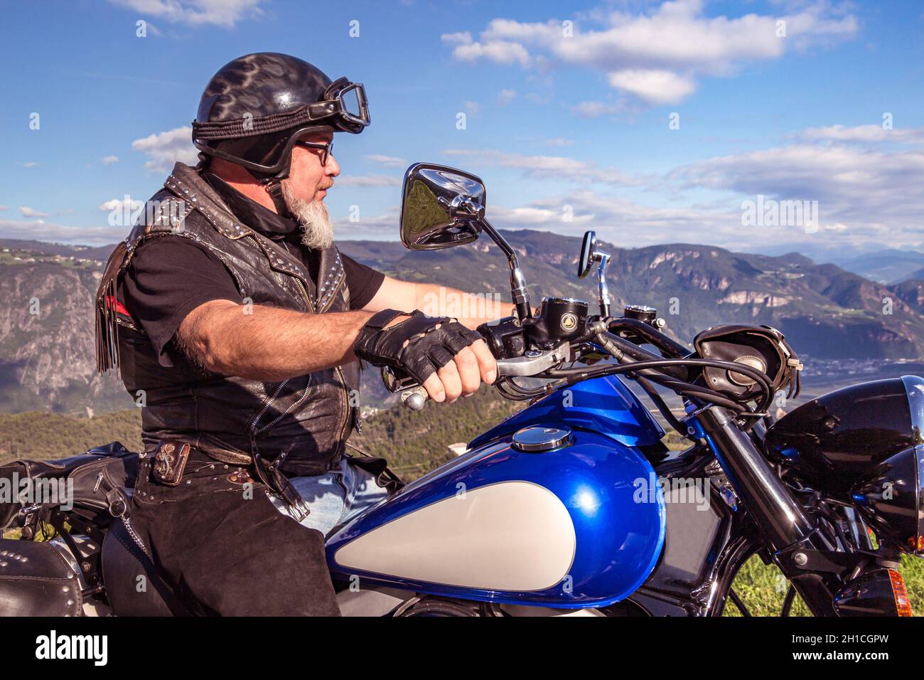 Un tipo que monta en una motocicleta de crucero retro en la carretera de montaña en el sur del tirol disfrutando de la hermosa vista Foto de stock