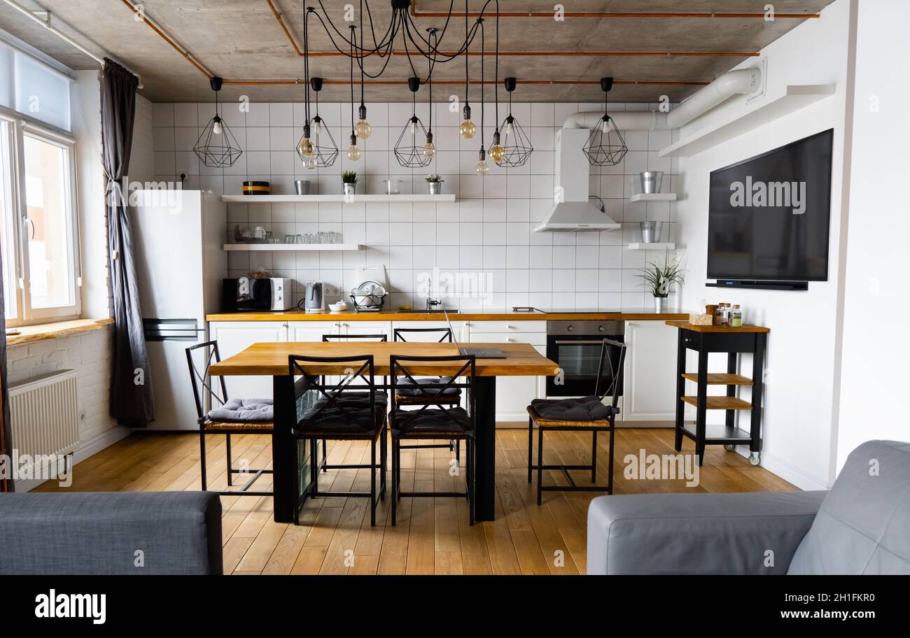 Un diseño interior de cocina comedor en estilo escandinavo moderno con una  gran mesa de madera y sillas contra pisos de madera clara, paredes y muebles  blancos brillantes Fotografía de stock -