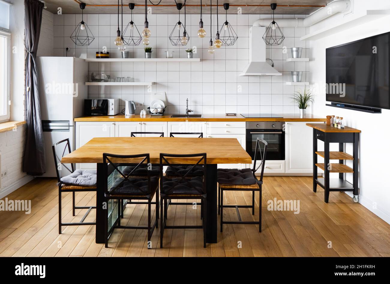Un diseño interior de cocina comedor en estilo escandinavo moderno con una  gran mesa de madera y sillas contra pisos de madera clara, paredes y  muebles blancos brillantes Fotografía de stock -