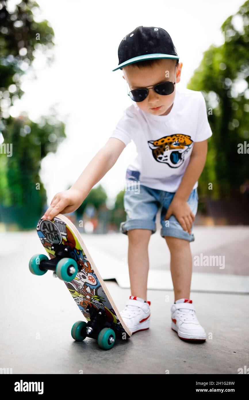 con un skate en un parque skate. Un niño con aprende a patinar con ropa elegante. Un poco extremo Fotografía de stock - Alamy
