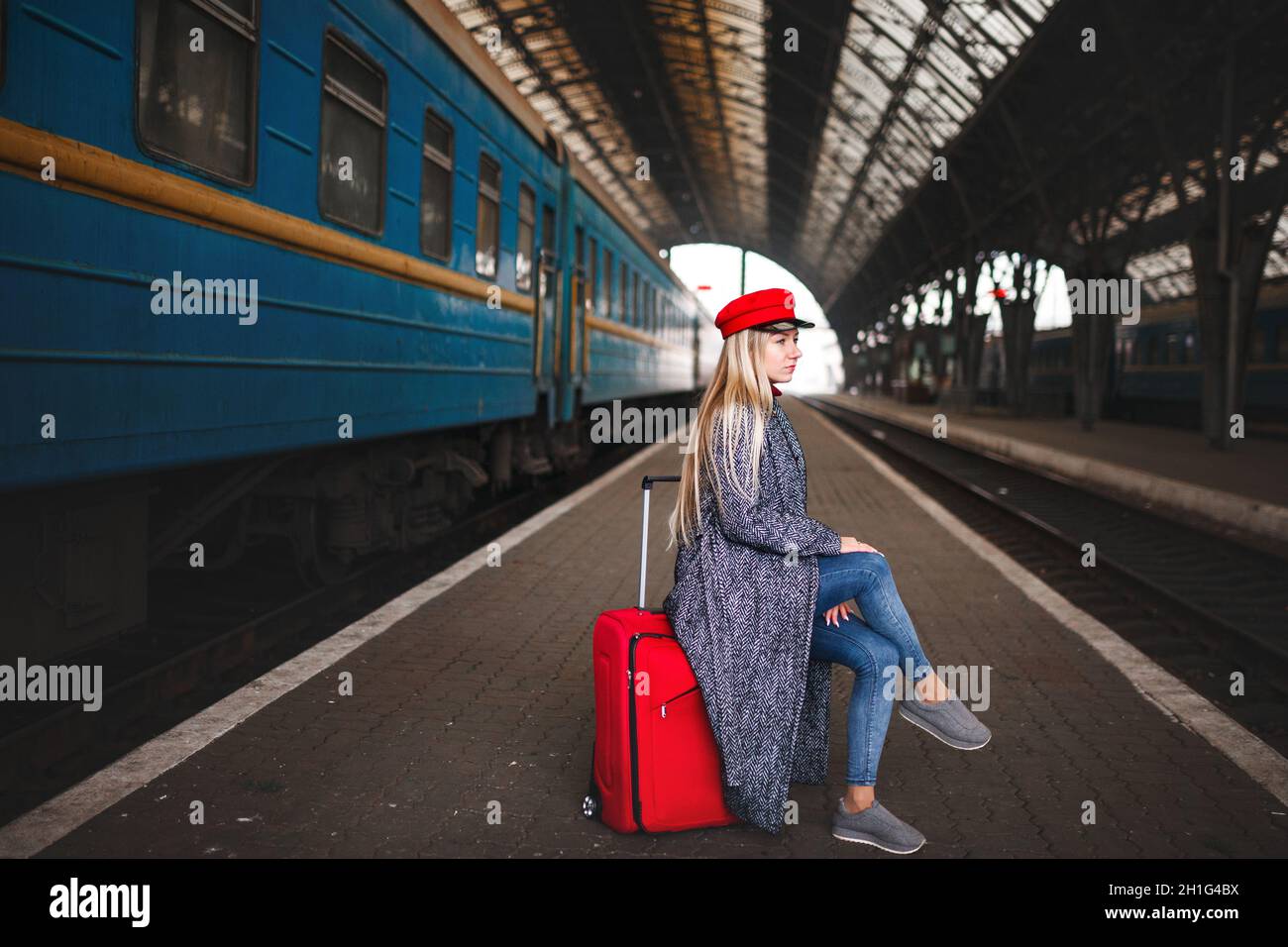 Estación de tren. Hermosa chica esperando el tren. La mujer viaja por el  mundo. Dama en un casquillo rojo y con una bolsa roja, geometría urbana  Fotografía de stock - Alamy