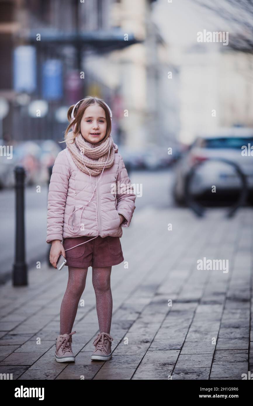 una niña feliz de 8-10 años con moderna escucha la música de su smartphone en los auriculares al aire libre. soleado en la ciudad. Outumn, Fotografía de stock - Alamy
