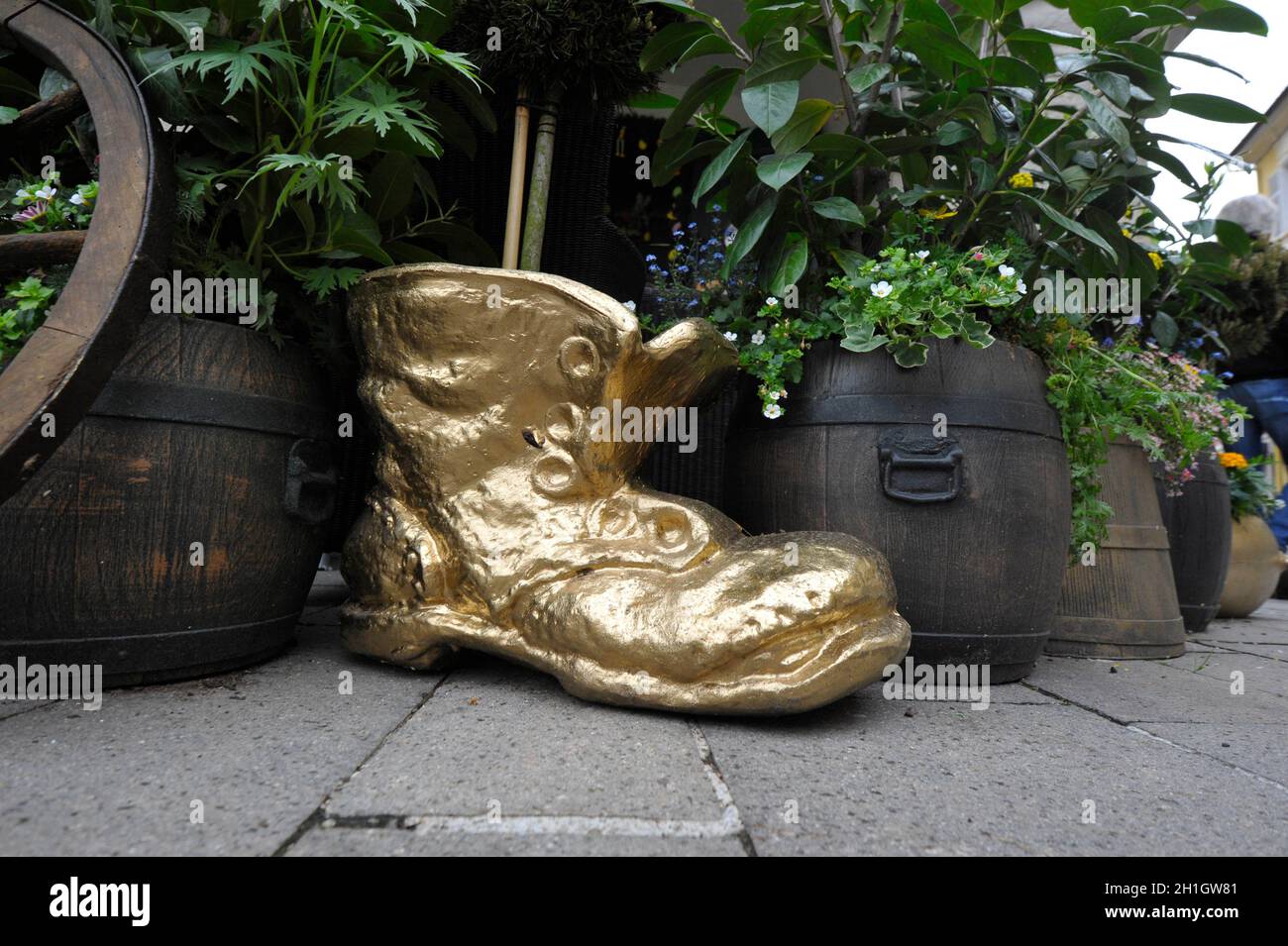 zapato dorado junto a barriles pequeños con plantas y una rueda de madera,  símbolo de zapatos o calzado Fotografía de stock - Alamy