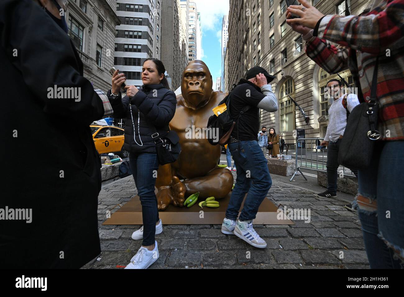 Nueva York,US, 18/10/2021, la gente se plantea junto a una instalación temporal de “Harambe”, una estatua de 7 pies de altura de un gorila, situada frente a la Bulla de Carga, como símbolo de protesta por la disparidad de la riqueza, una protesta organizada por Sapien Network, en Bowling Green Park, Nueva York, NY, 18 de octubre de 2021. Se colocaron miles de plátanos alrededor de la bula de carga y luego se retiraron para su distribución a los pantry de alimentos. (Foto de Anthony Behar/Sipa USA) Foto de stock