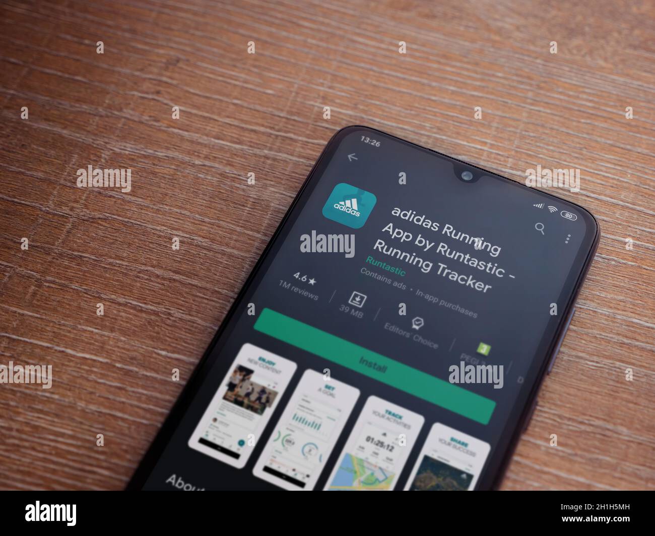 LOD, Israel - 8 de julio de Adidas running app play store page en la pantalla de un smartphone móvil negro sobre fondo de madera. Vista superior plano de la cama