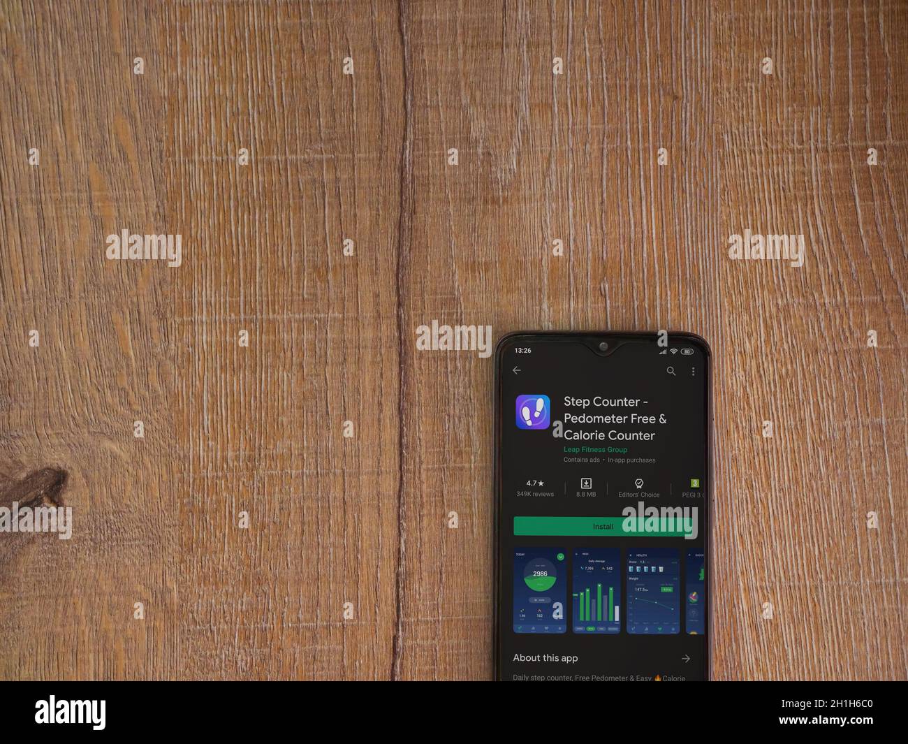 LOD, Israel - 8 de julio de 2020: Step Counter aplicación jugar tienda página en la pantalla de un teléfono inteligente negro sobre fondo de madera. Vista superior plana con Foto de stock