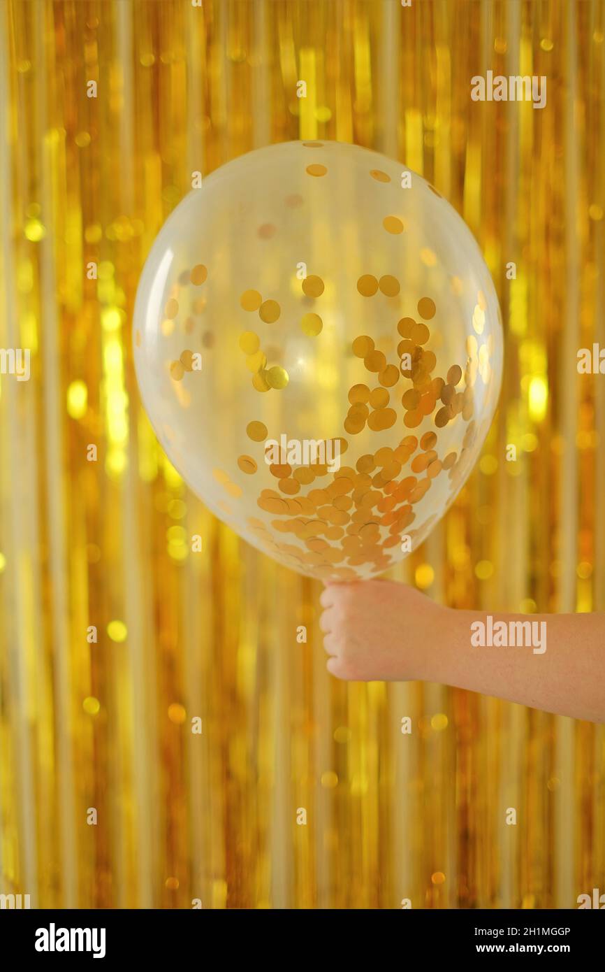 Niños vacaciones.Cumpleaños de fondo. Globo con kanfeti en la mano de un niño sobre un fondo de piel dorada. Año Nuevo y Navidad time.festive Foto de stock