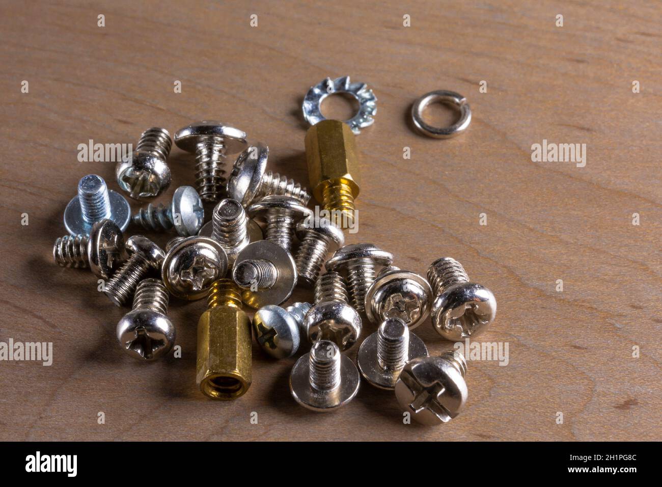 Un conjunto de pequeños tornillos de computadora chapados en níquel  esparcidos sobre una mesa de madera Fotografía de stock - Alamy