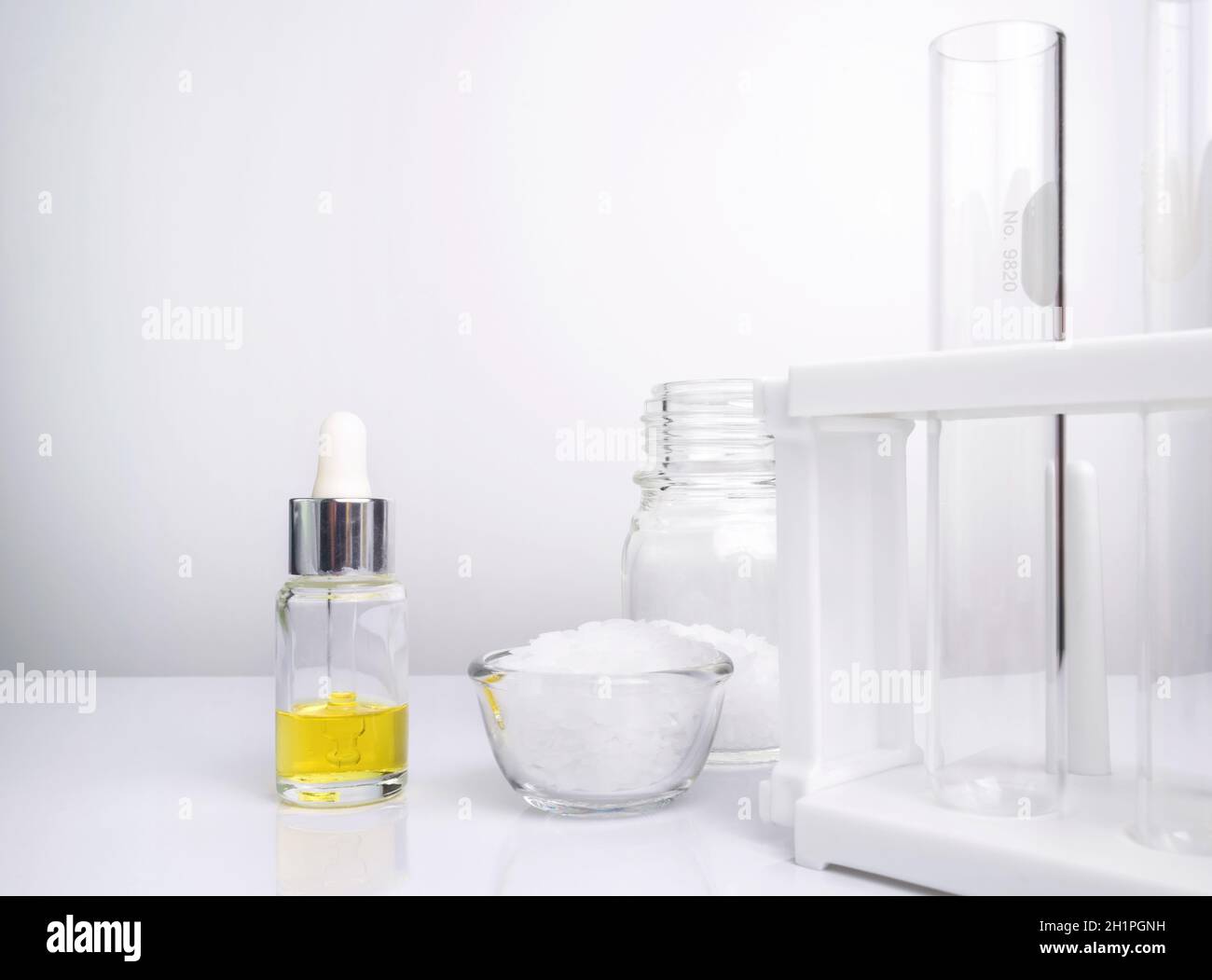 Ingredientes químicos cosméticos sobre mesa blanca de laboratorio. Etanolamina, ácido, alcohol cetílico, Color cosmético amarillo (aceite), cera microcristalina Foto de stock