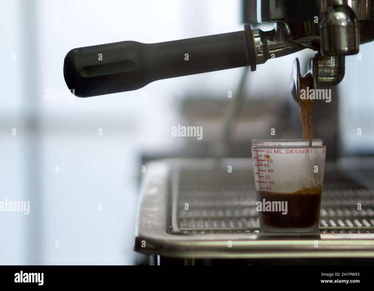 Cafetera espresso verter café en taza de medir. De cerca Foto de stock