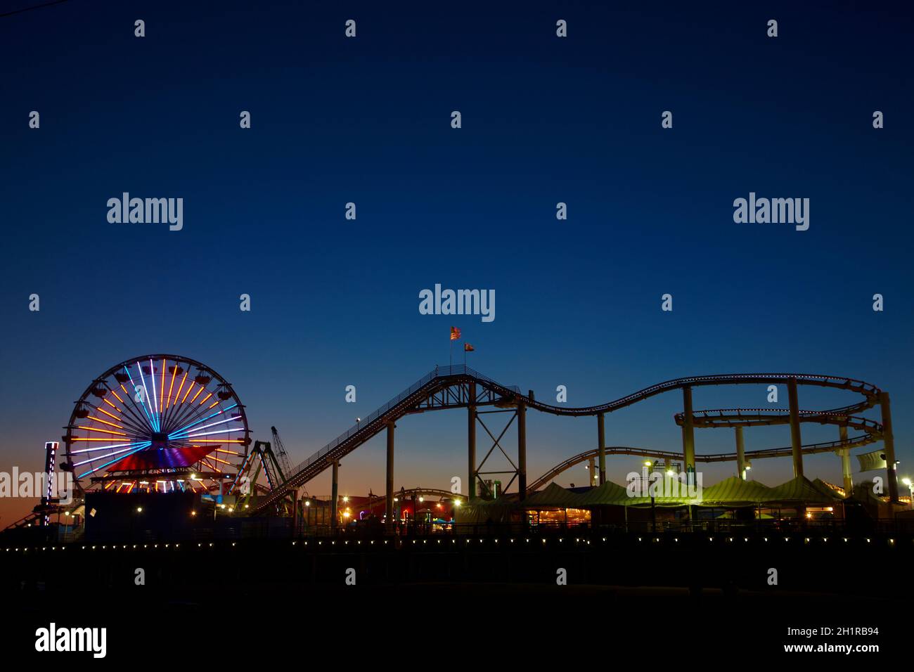 Rueda de Ferris y roller coaster al anochecer, Pacific Park, Santa Monica Pier, Santa Monica, Los Ángeles, California, Estados Unidos. Foto de stock