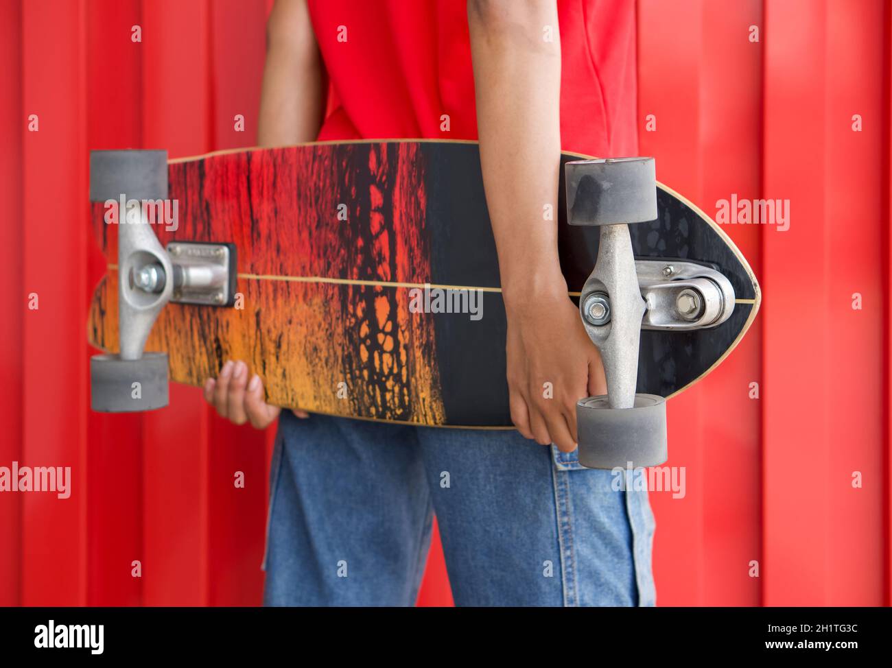 Primer plano surfskates tablero en las manos de adolescente en una posición de la cadera. Foto de stock