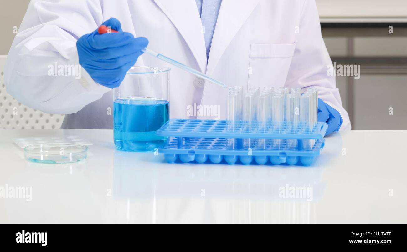 Científicos en camisa azul y bata de laboratorio hacen experimentos en un laboratorio científico. Enfoque suave Uso para fondo. Foto de stock