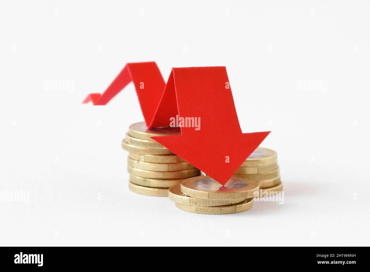 Pilas de monedas en euros con flecha roja descendente - concepto de pérdida de dinero Foto de stock