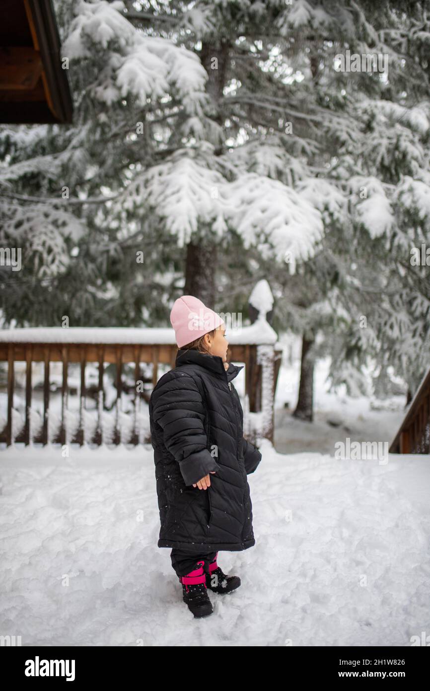 Feliz niña con chaqueta de gran tamaño y de sobre la nieve. Niño pequeño divirtiéndose en el día nevado. Vacaciones de invierno aventureras Fotografía stock - Alamy
