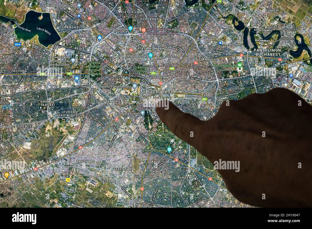 Udine, Italia. 21 de agosto de 2021. La vista de satélite de Goobble Maps de Bucarest, capital de Romnania, indicada con un dedo Foto de stock