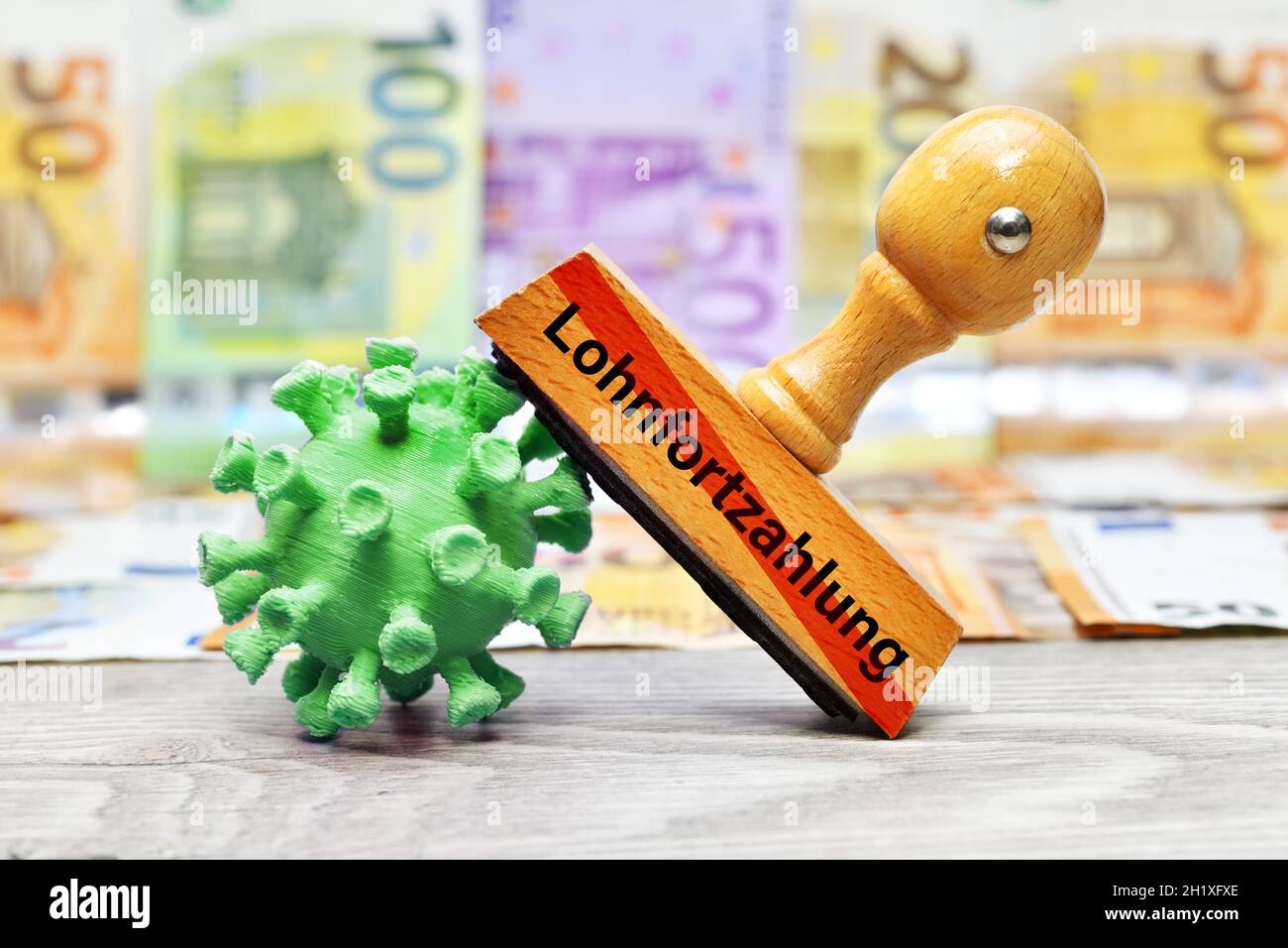 Palabra alemana para el pago continuado de salarios en el sello junto al modelo del coronavirus Foto de stock