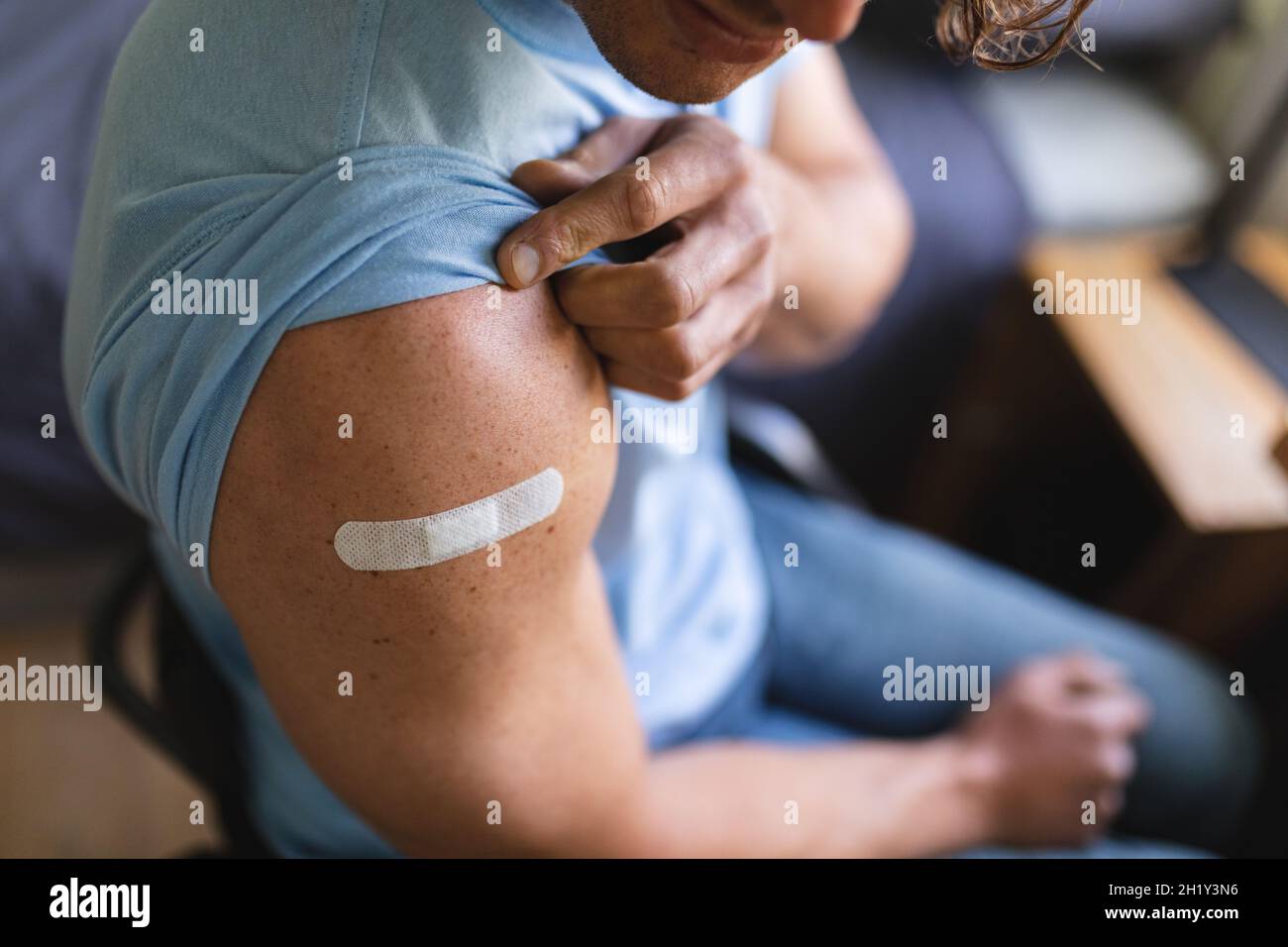 Sección media de hombre con discapacidad caucásica mostrando su hombro vacunado en casa Foto de stock