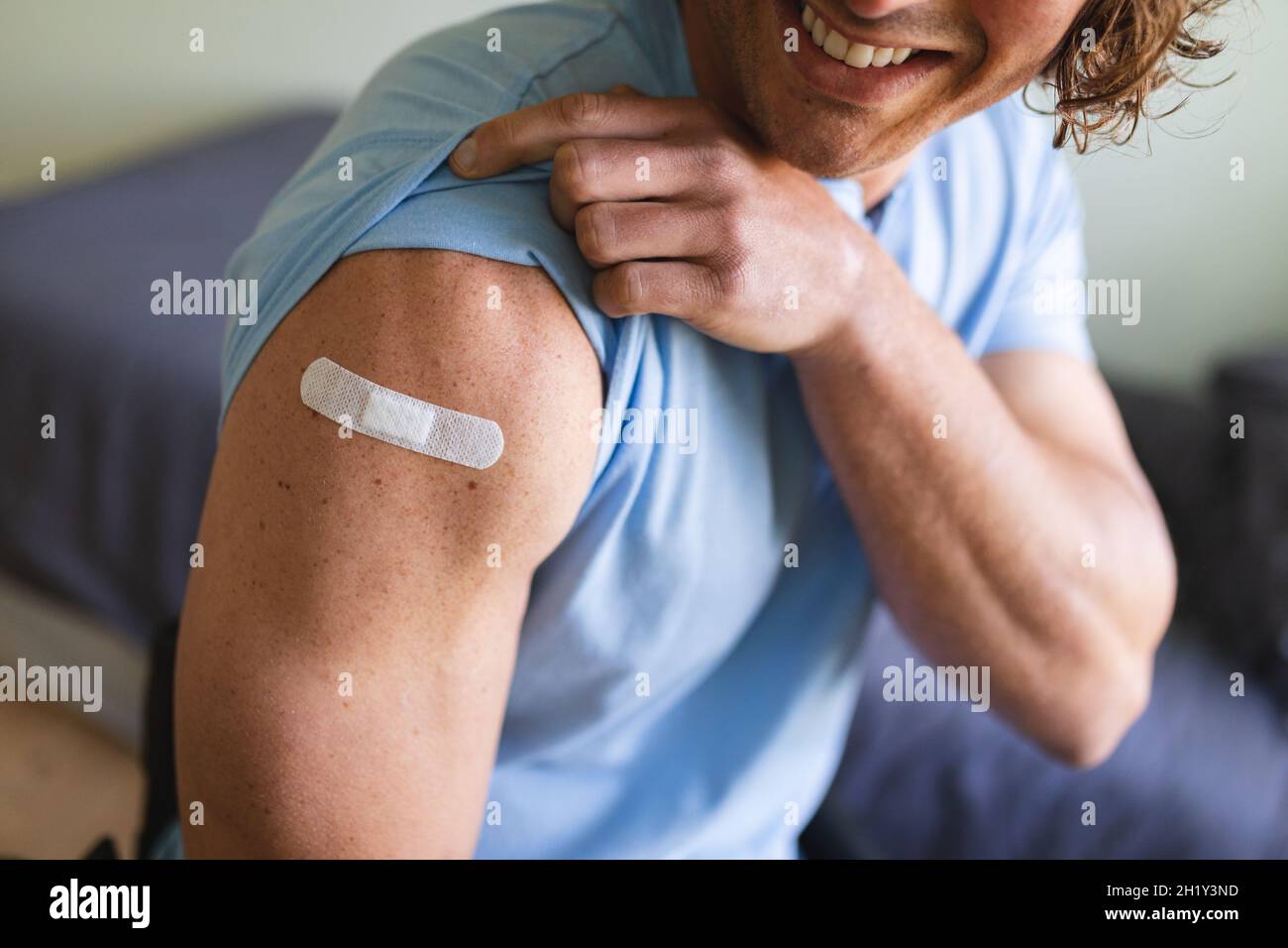 Sección media de hombre con discapacidad caucásica mostrando su hombro vacunado en casa Foto de stock