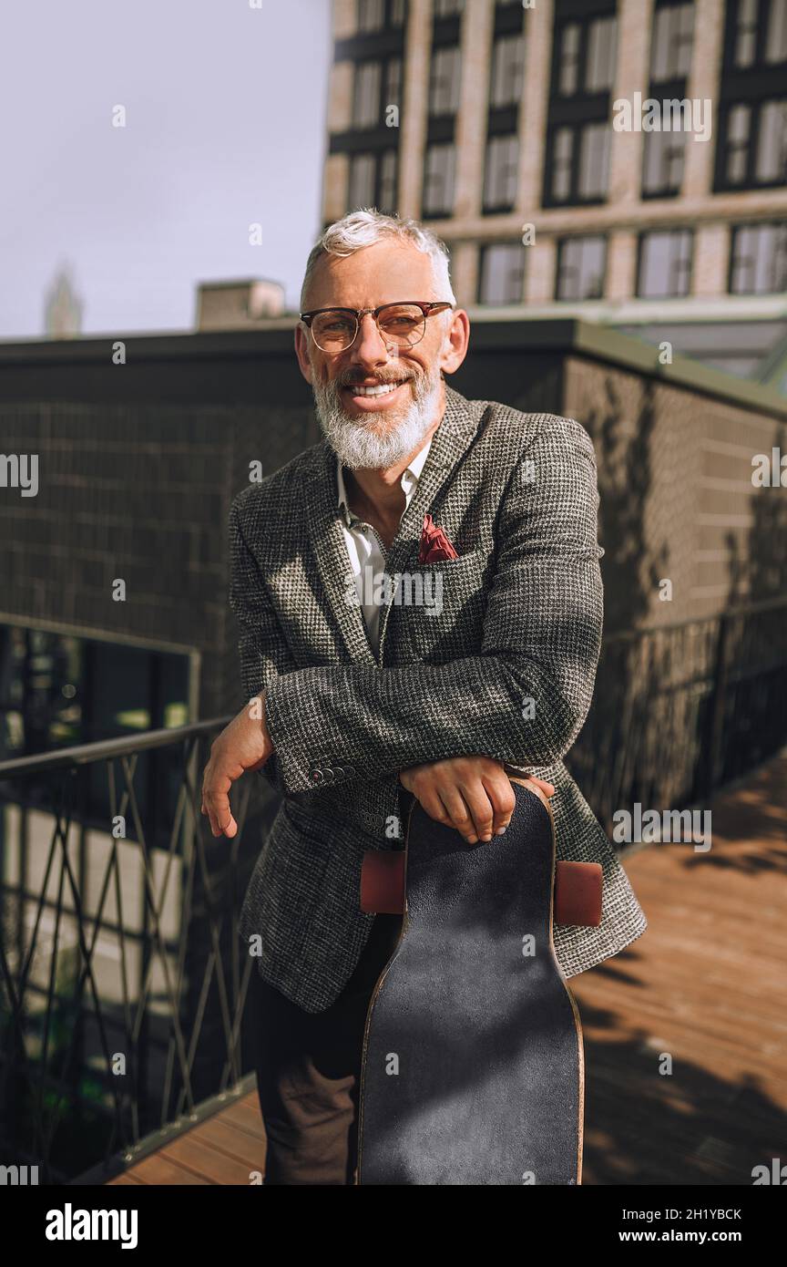 Un hombre de pelo gris que mira bien sonriendo y mirando positivo Foto de stock