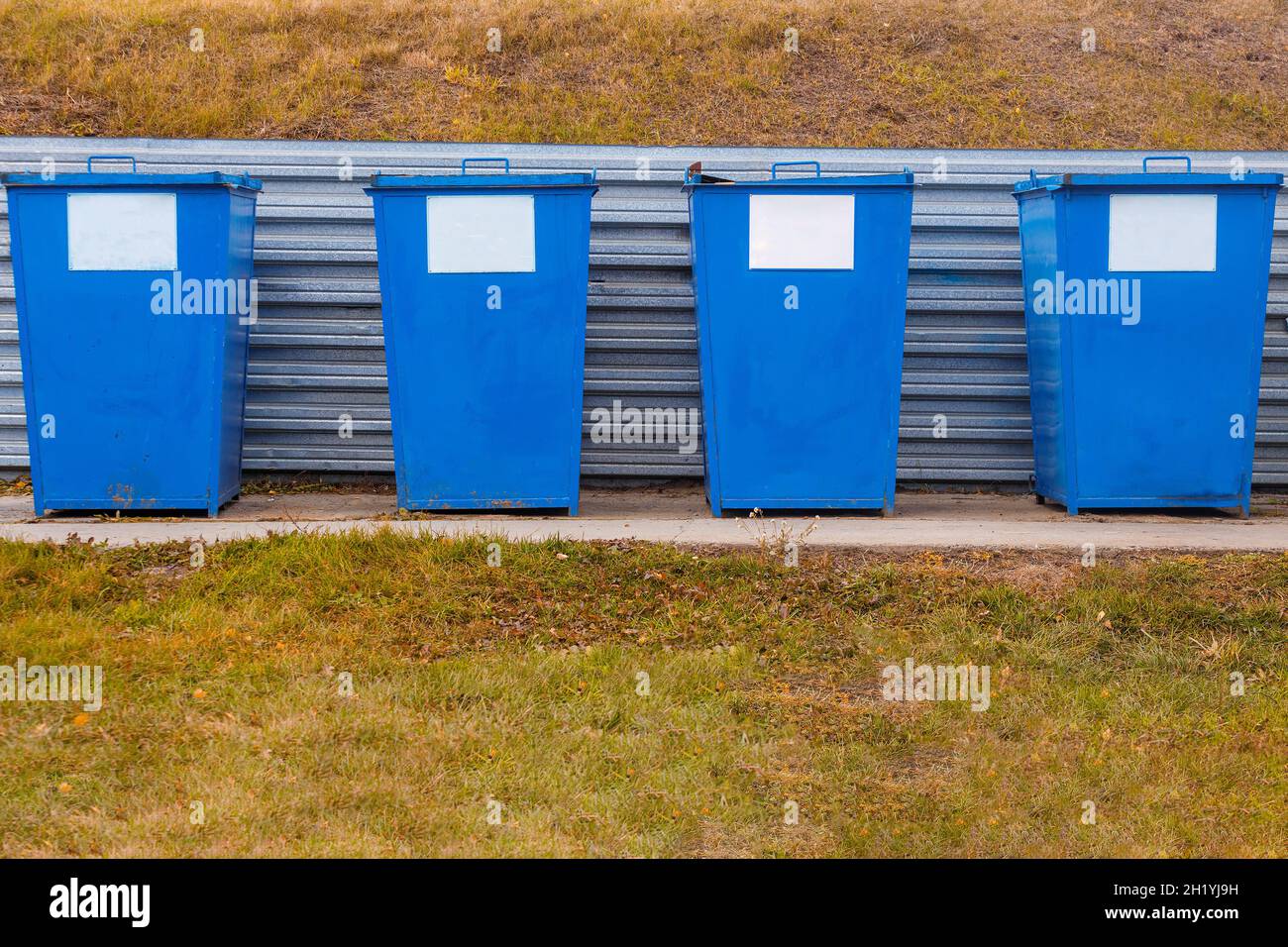 Las latas de basura de metal de color azul se encuentran en una zona especial al aire libre en un día de verano. Eliminación de residuos. Limpieza y cuidado del medio ambiente. Foto de stock