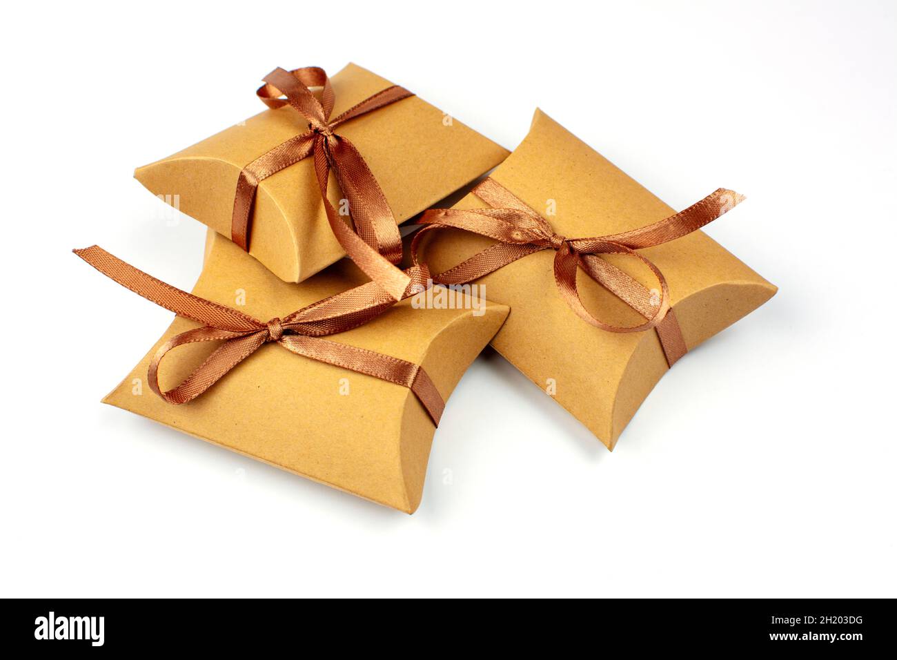 Pequeños regalos en una caja de cartón natural. La caja de artesanía está  atada con una cinta de satén marrón. Grupo de regalos, espacio de copia.  Cajas de regalo con reciclado Fotografía