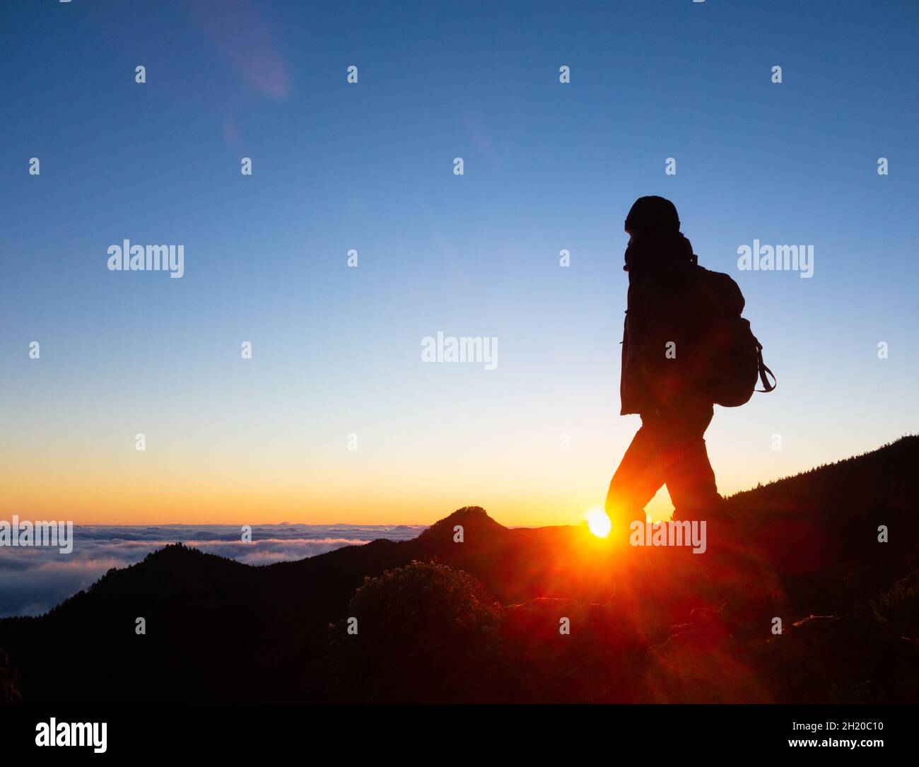 Mujer, caminadora mujer, caminando, caminando en montañas por encima de la conversión de nubes al amanecer. Foto de stock