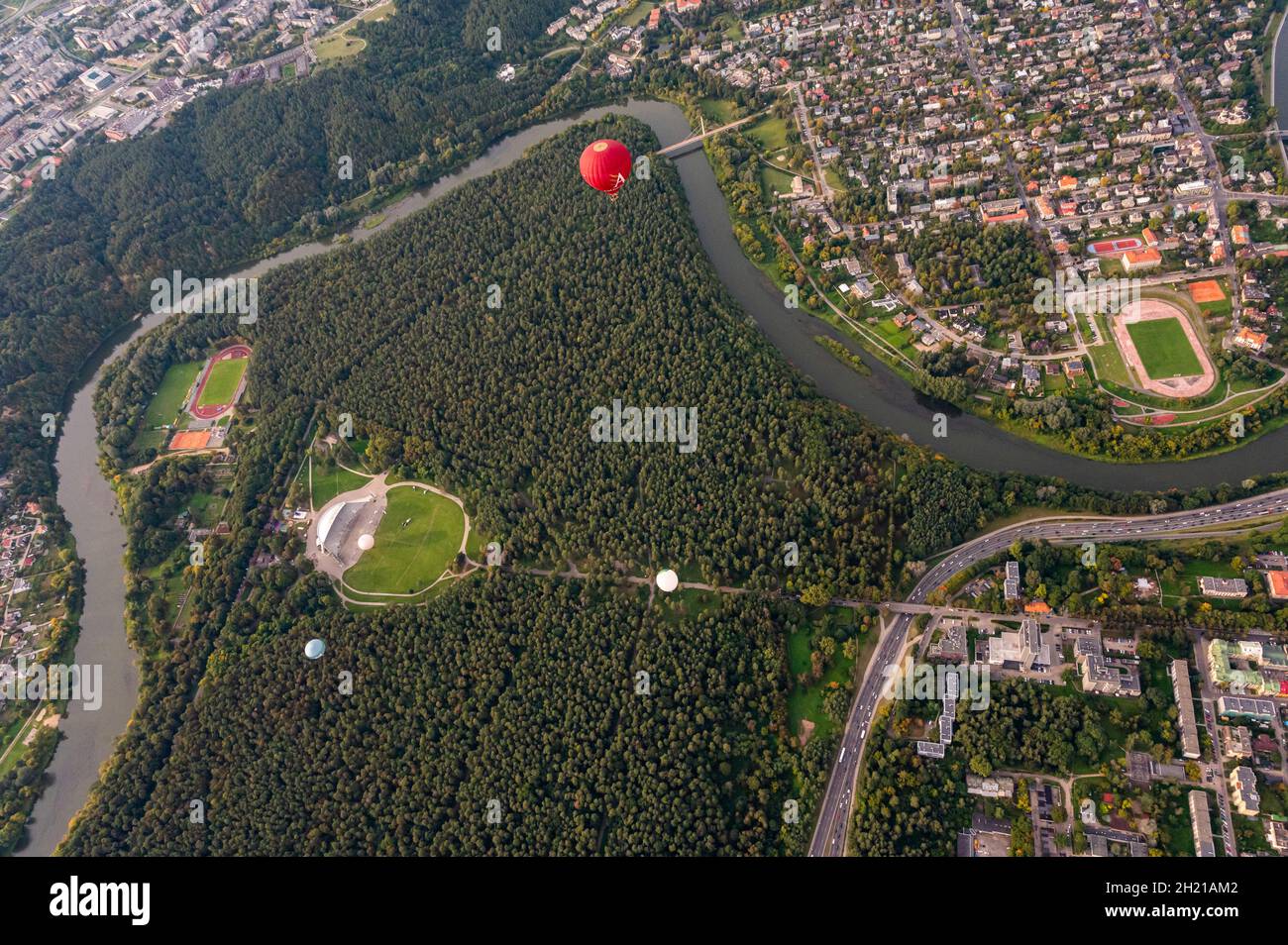 Vilnius, Lituania - 14 de septiembre de 2021: Vibrante globo de aire caliente rojo volando sobre la capital de Vilnius, Lituania. Distrito de Zverynas y parque de Vingis surr Foto de stock