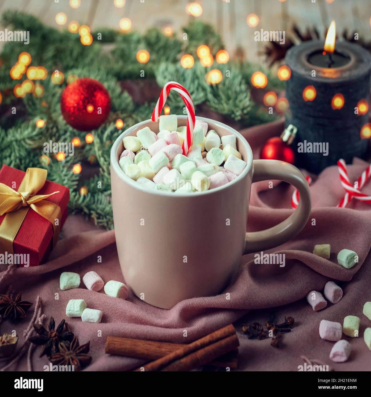 Taza de cacao y malvaviscos en la bufanda rosa, rama de abeto con luces de  Navidad, vela y caja de regalo. Concepto de Navidad, vacaciones de  invierno. Primer plano Fotografía de stock -