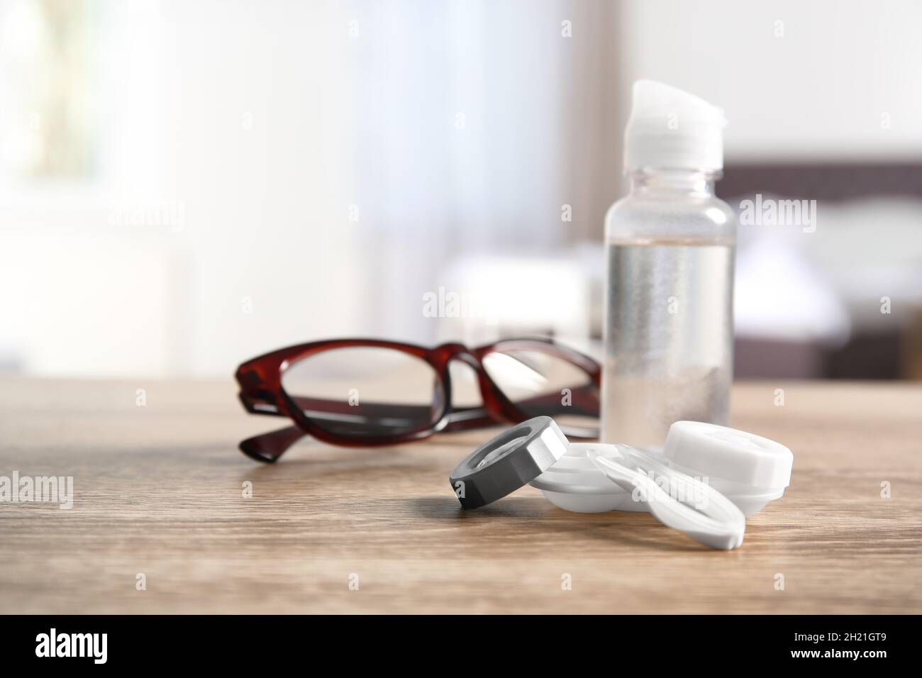 Funda para lentes de contacto, pinzas, botella de solución y gafas sobre la mesa Fotografía de Alamy