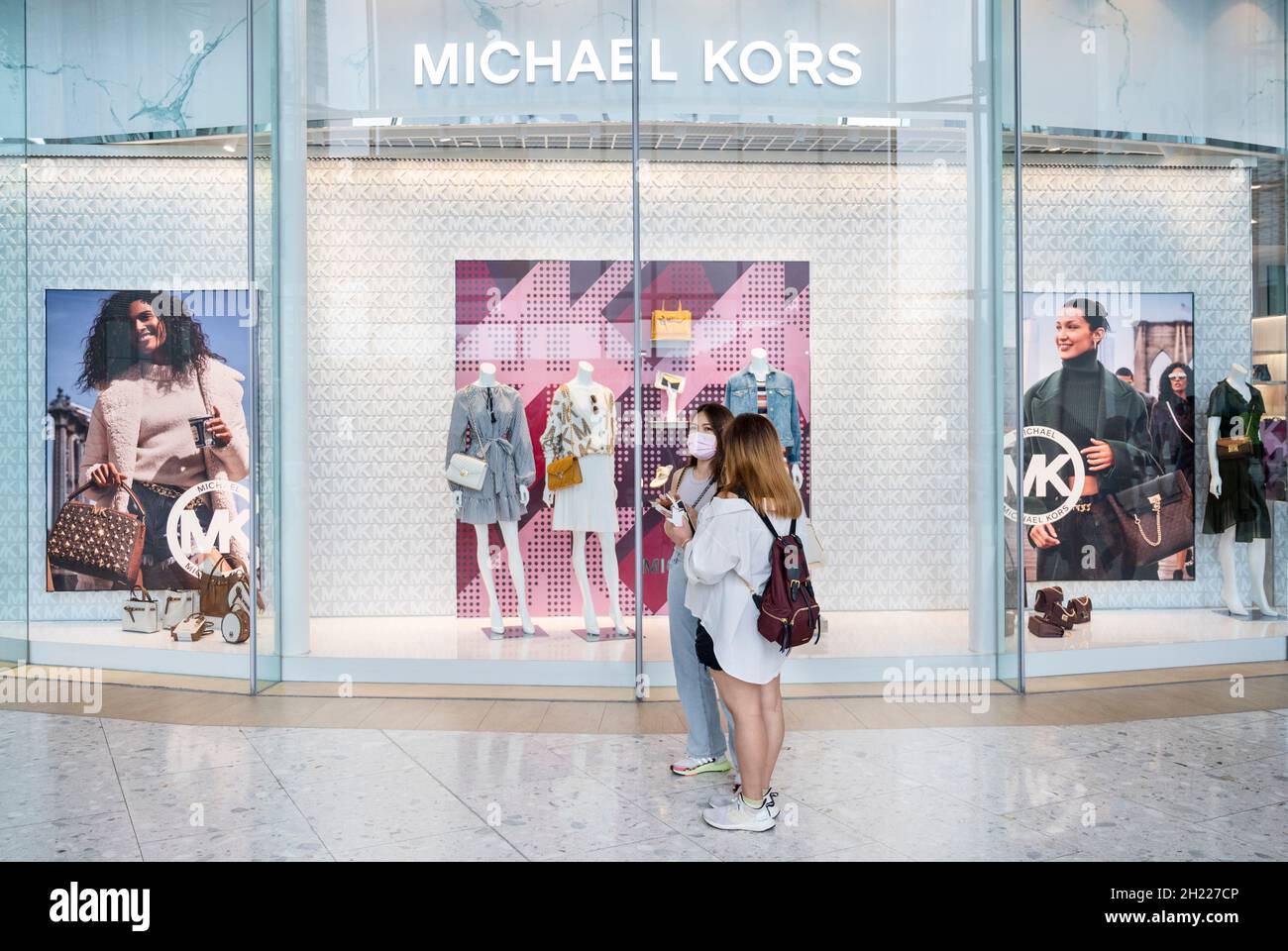 Los compradores se encuentran fuera del logotipo de la tienda de moda de  ropa estadounidense Michael Kors (MK) y se almacenan en el distrito de Tung  Chung en Hong Kong. (Foto de