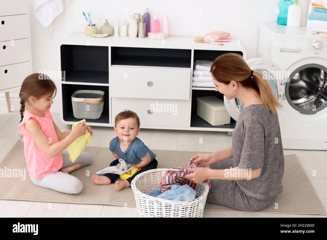 Ama de casa con niños doblando recién lavada en la Fotografía de stock - Alamy