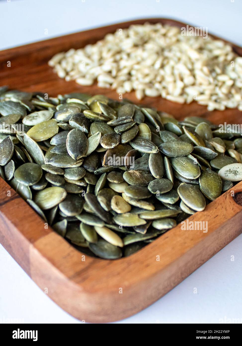 Semillas de calabaza y girasol en un plato de madera sobre fondo blanco  Fotografía de stock - Alamy