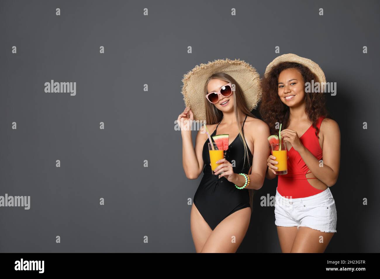 Hermosas mujeres jóvenes en ropa de playa con cócteles sobre fondo oscuro.  Espacio para texto Fotografía de stock - Alamy