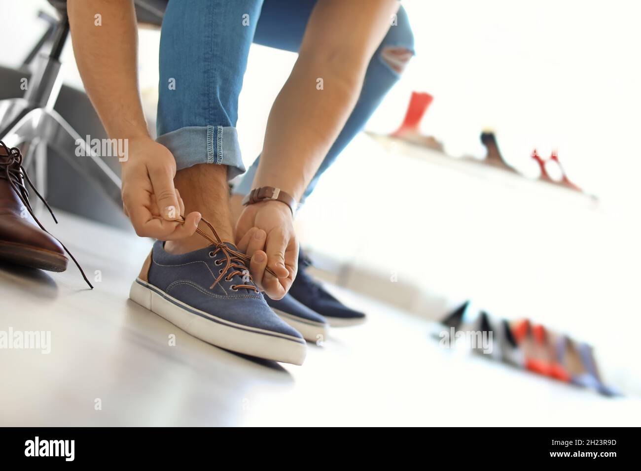Riego suelo desvanecerse Hombre joven tratando de zapatos en la tienda Fotografía de stock - Alamy