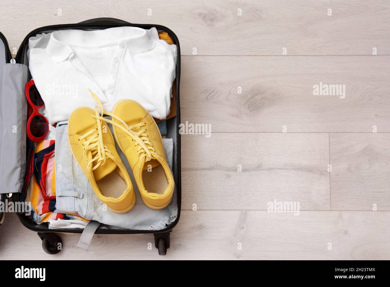 Maleta con ropa y sneakers sobre fondo de madera, vista superior. Espacio  para texto Fotografía de stock - Alamy