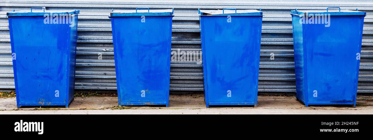 Las latas de basura de metal de color azul se encuentran en una zona especial al aire libre en un día de verano. Eliminación de residuos. Limpieza y cuidado del medio ambiente. Foto de stock