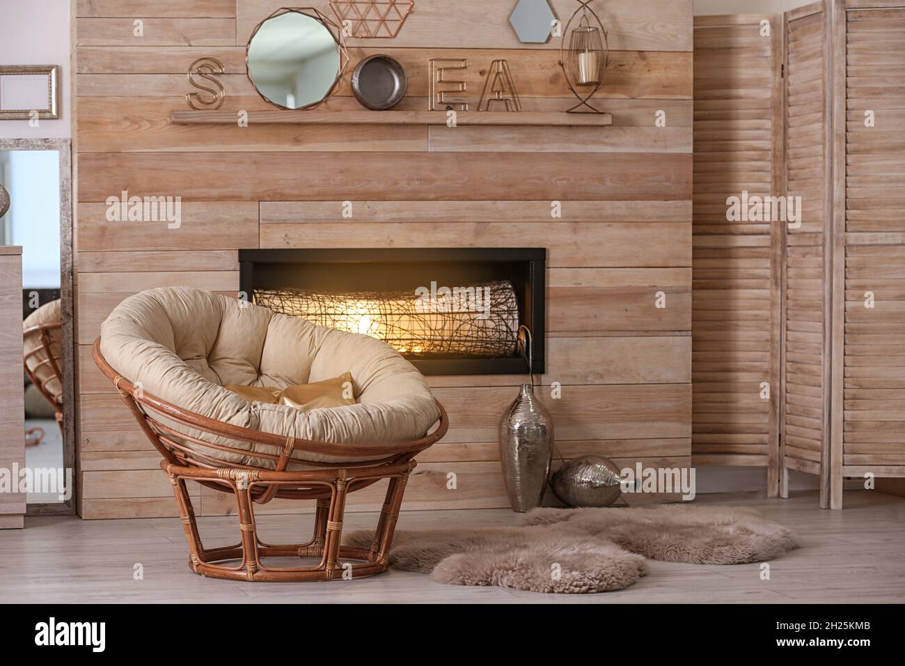 Acogedor salón interior con una cómoda silla papasana y chimenea decorativa  Fotografía de stock - Alamy