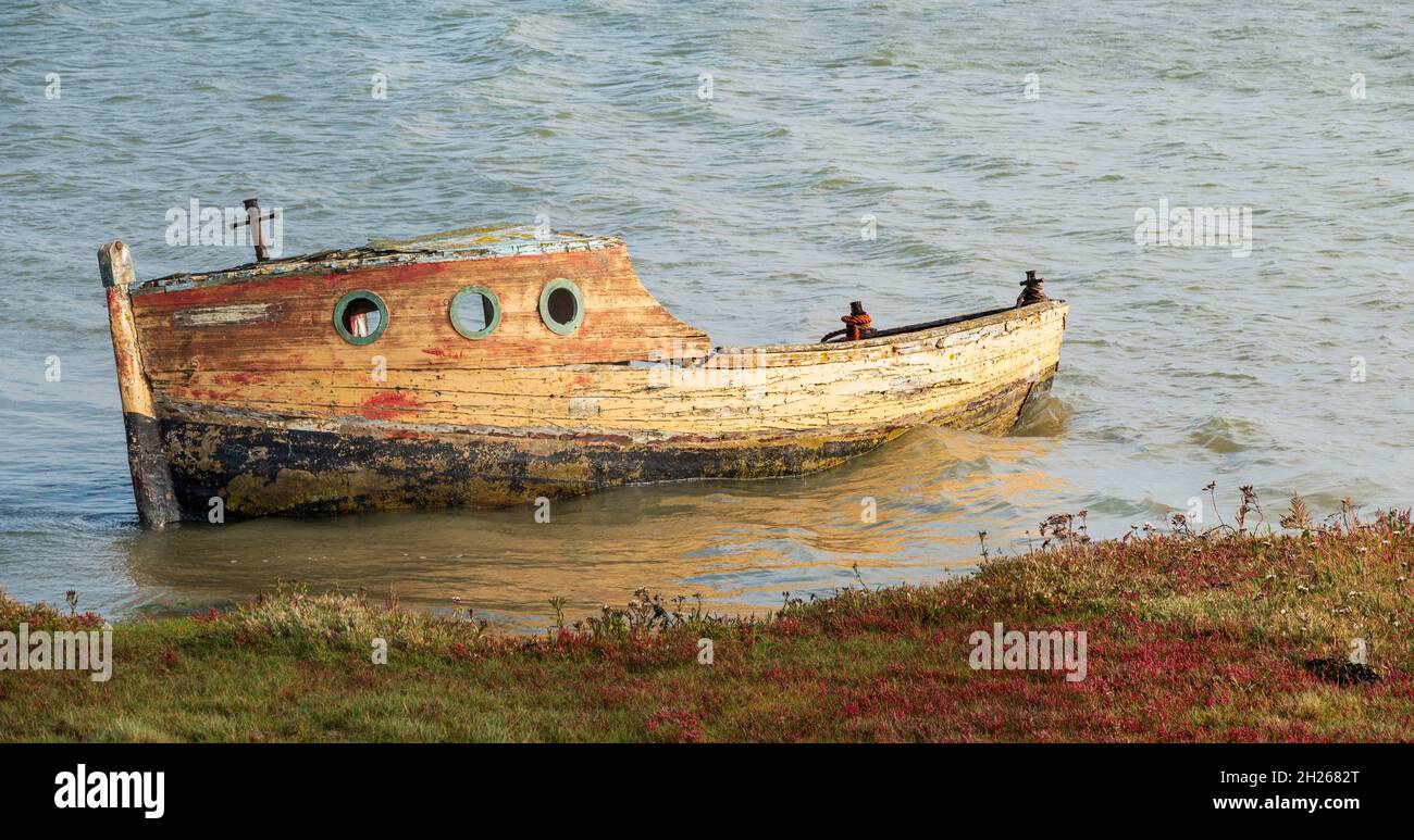 Abandonado clinker construyó un barco parcialmente sumergido en una orilla del río Foto de stock
