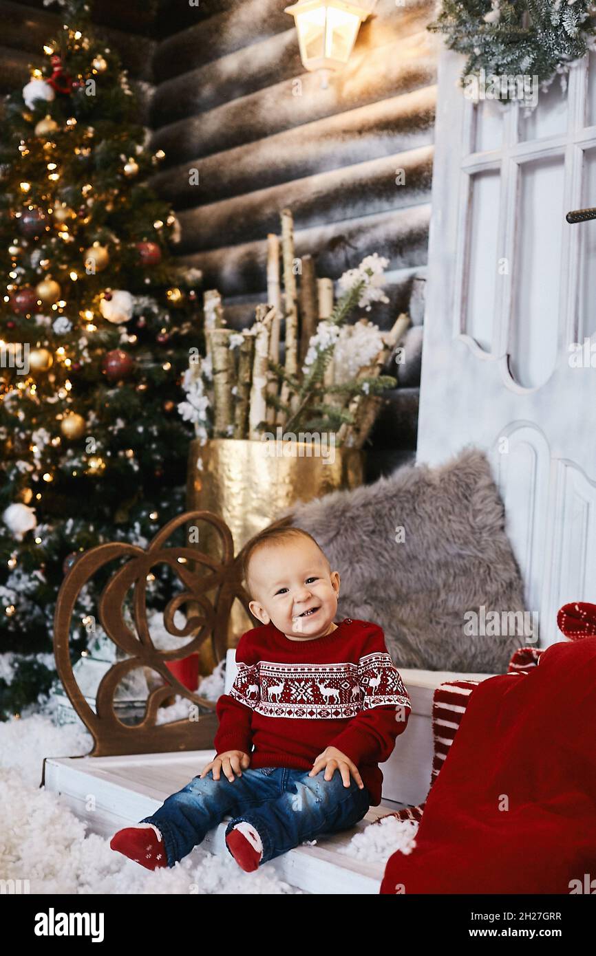 Lindo niño en un suéter feo posando en las escaleras de la casa decorada  para Navidad Fotografía de stock - Alamy