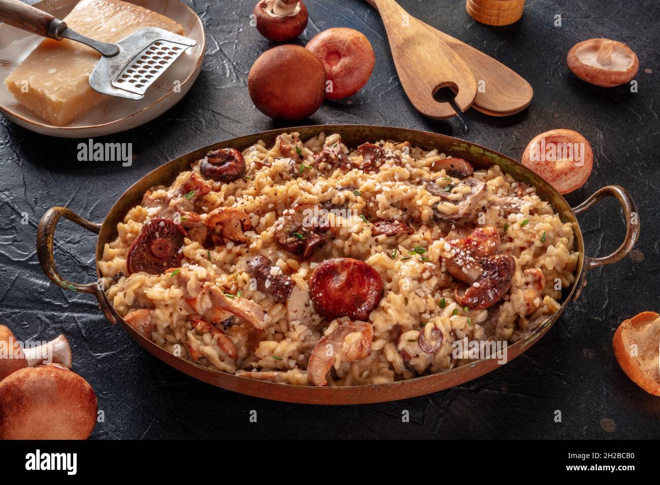 Risotto ai funghi, arroz de champiñones, con ingredientes, sobre fondo negro Foto de stock