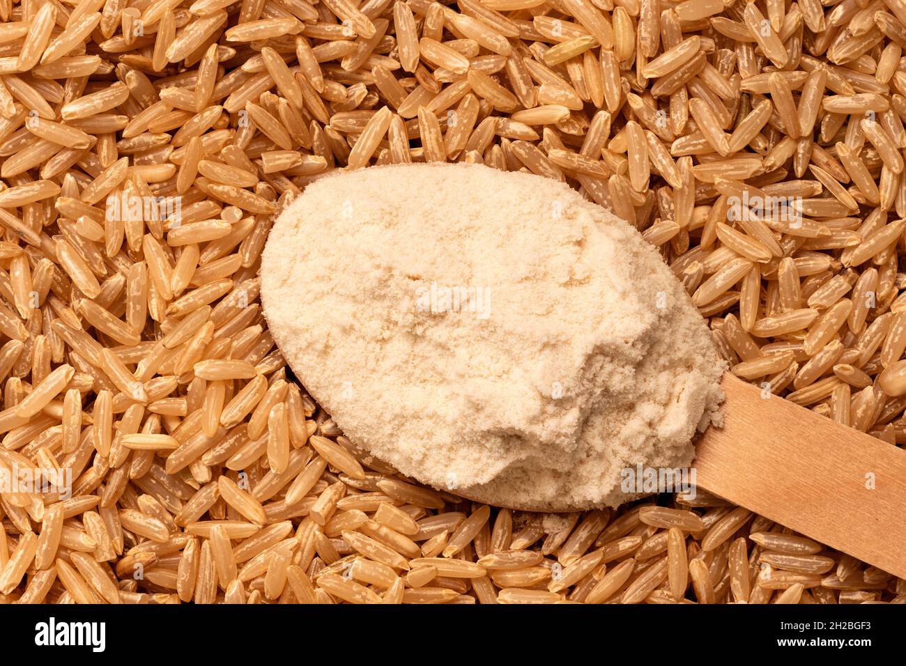 Cuchara colmada de harina de arroz integral sobre arroz integral. Vista superior. Antecedentes. Foto de stock